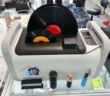 Record cleaner with vinyl records on a display stand in a store setting
